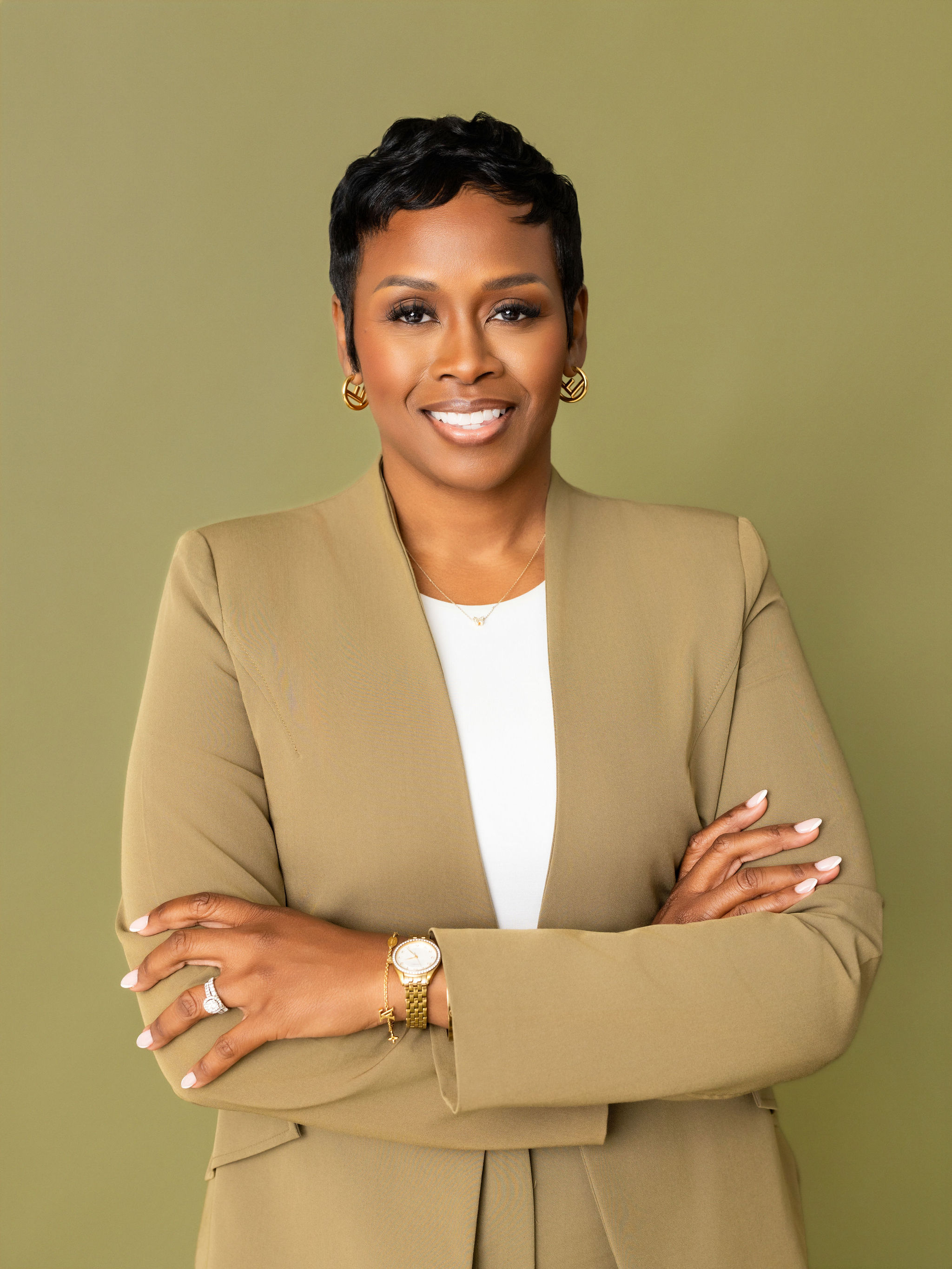 Autumn Russell smiling in a tan blazer against an olive background